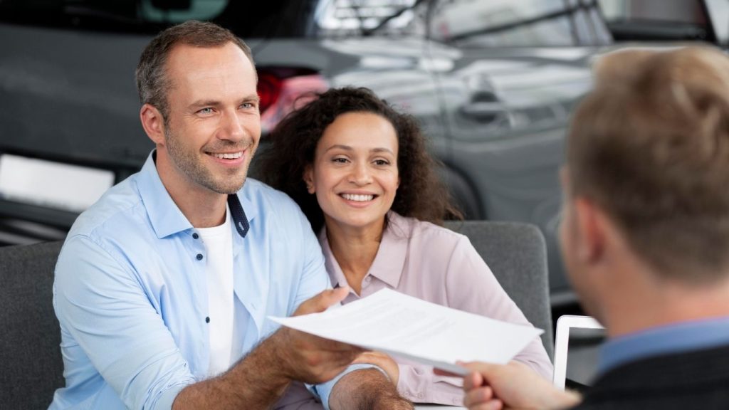 Affordable Auto Insurance Pearland TX | Trusted Coverage 25 Smiling couple signing an Auto Insurance Pearland TX agreement with an insurance agent.