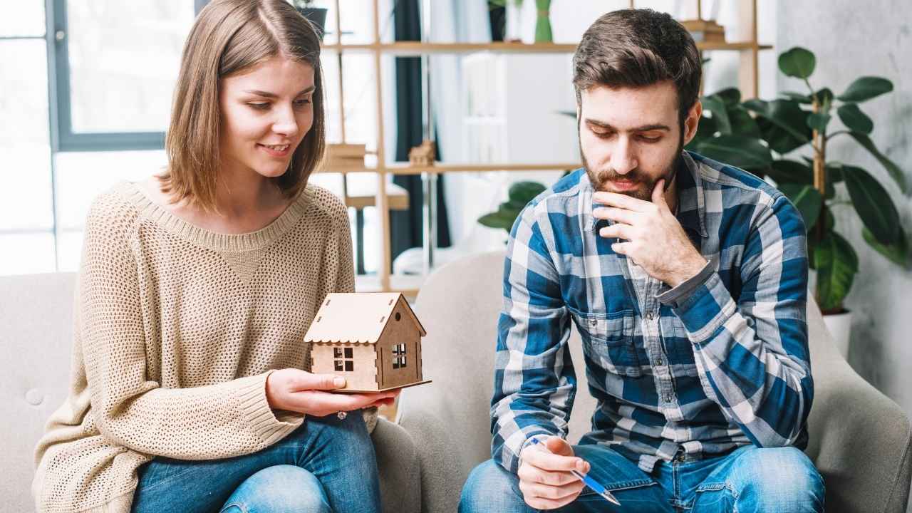 A couple discussing Evansville home insurance options while holding a small wooden house model